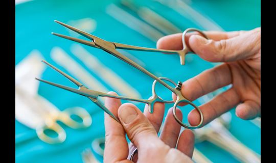 Hands holding two pairs of forceps and comparing them