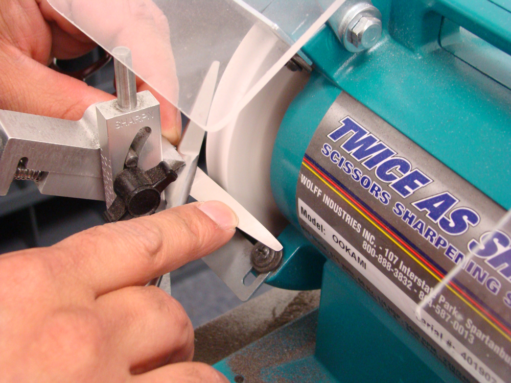 Hand sharpening scissors on a machine.