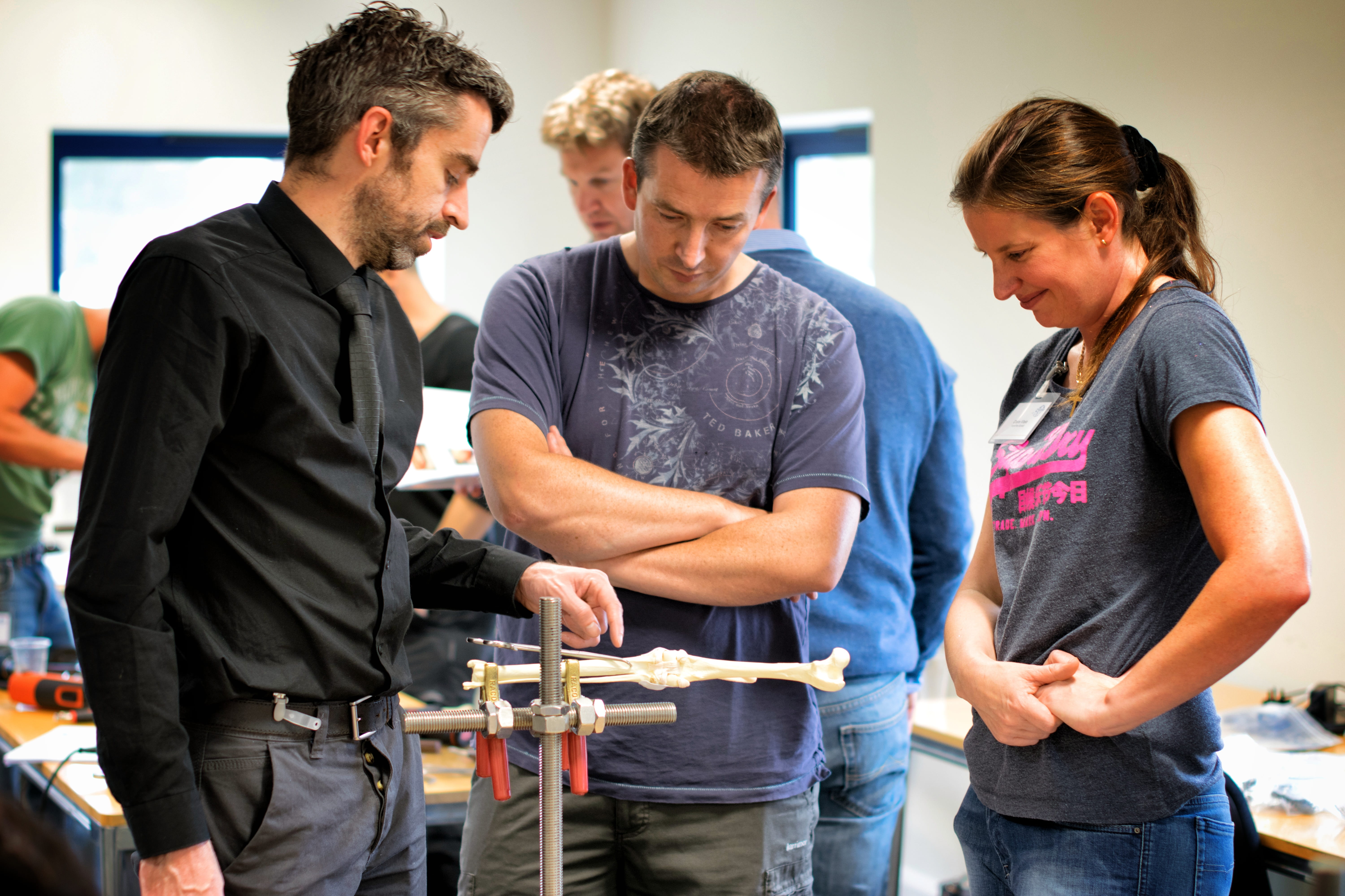 Three people in a wet lab looking at a bone model
